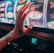 A hand with tattoos reaches towards a brightly lit slot machine, featuring various colorful symbols including a tiger. The image captures the moment of anticipation as the person engages with the machine during a game of chance.